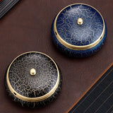 Two decorative brass ashtrays with blue and black cracked surface and gold accents