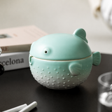 Green ceramic pufferfish ashtray with lid on dark tabletop