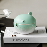 Green ceramic pufferfish ashtray with lid on newspaper table