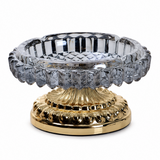 Smoke gray faceted glass ashtray with ornate gold metal stand on white background