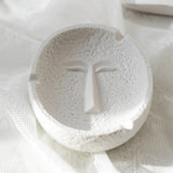 Calm face expression ceramic ashtray in white, minimalist round tabletop design