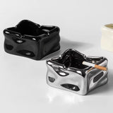Two ceramic ashtrays, one black and one silver