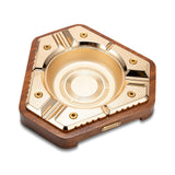 Modern hexagon cigar ashtray in brushed gold with solid wood base on white background
