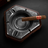 Glossy black hexagon cigar ashtray with cigar on a dark tabletop