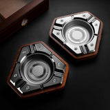 Glossy black and silver alloy cigar ashtrays displayed side by side on a dark background