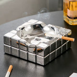 Silver cube ashtray with cigarette on black table, stylish modern ashtray for home or lounge