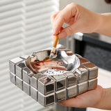 Modern silver cube ashtray in use, handheld lifestyle photo with cigarette and deep ash bowl