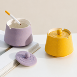 Lavender ceramic ashtray with cigarette beside closed mustard yellow ashtray