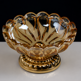Amber scalloped glass ashtray with gold metal base on dark background