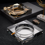 Gold square crystal ashtray with cigarette on dark table luxury setting