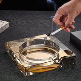 Hand using gold crystal ashtray square heavy glass close up usage