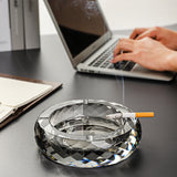 Clear glass ashtray on desk near laptop modern workspace setting