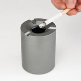 Outdoor ashtray with rotatable lid used to extinguish a cigarette